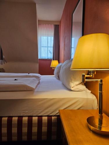 um quarto de hotel com uma cama e uma mesa com um candeeiro em Landhotel Ölmühle em Mömbris