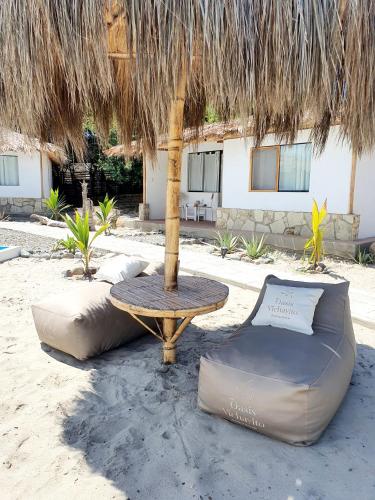 a table and chairs under a straw umbrella at Oasis de Vichayito in Vichayito
