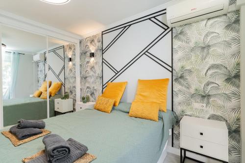 1 dormitorio con 2 camas y almohadas amarillas en MalagadeVacaciones - La Carihuela, en Torremolinos