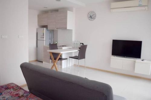 Acqua Apartment في جومتين بيتش: غرفة معيشة مع أريكة وطاولة مع كراسي