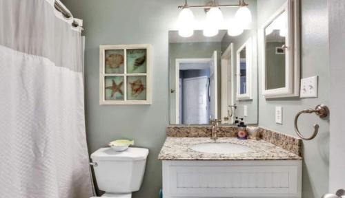 uma casa de banho com um lavatório, um WC e um espelho. em Sea Grace em Carolina Beach