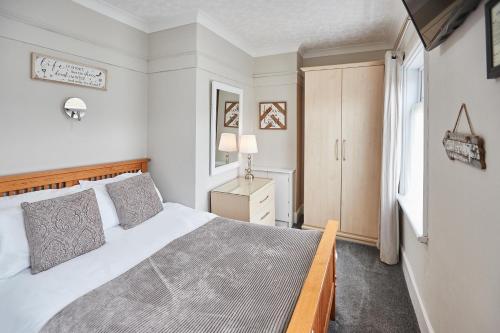 Un dormitorio con una gran cama blanca y una ventana en Glencoe Holiday Apartments Whitby, en Whitby