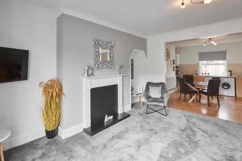 a living room with a fireplace and a dining room at Glencoe Holiday Apartments Whitby in Whitby