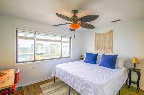 een slaapkamer met een bed met blauwe kussens en een plafondventilator bij Boho at the Beach in Carolina Beach