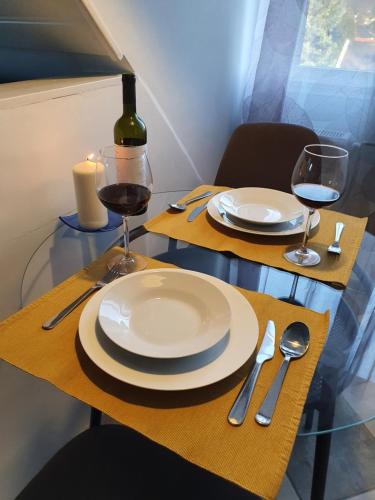 a table with two white plates and glasses of wine at Zöld Relax Apartments in Budakeszi
