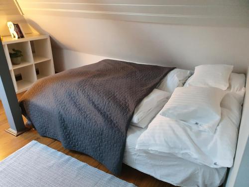 a bed with white sheets and a brown blanket at Zöld Relax Apartments in Budakeszi
