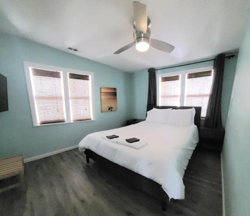 um quarto com uma grande cama branca e uma ventoinha de tecto em Beachwood Bungalow A em Carolina Beach