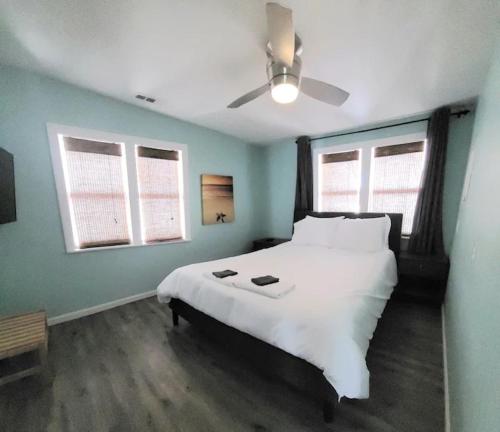 um quarto com uma grande cama branca e 2 janelas em Beachwood Bungalow B em Carolina Beach