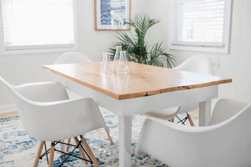 a white dining room with a wooden table and white chairs at Island Time in Carolina Beach