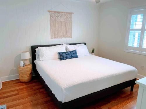 a bedroom with a bed with white sheets and blue pillows at Vitamin Sea in Carolina Beach