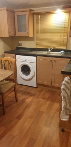 uma cozinha com uma máquina de lavar roupa e um lavatório em 2 bed caravan parkdean saltfleet near mablethorpe em Saltfleet
