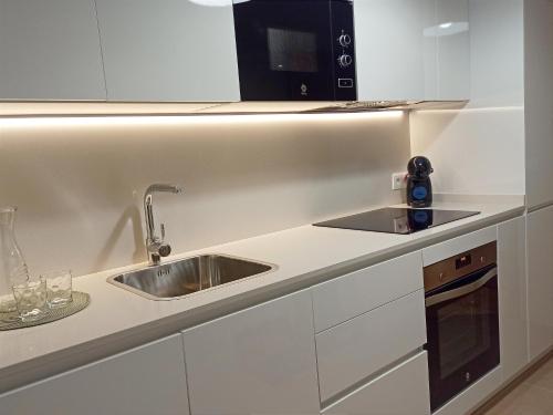 a white kitchen with a sink and a microwave at Aronda Cambados apartamento céntrico in Cambados