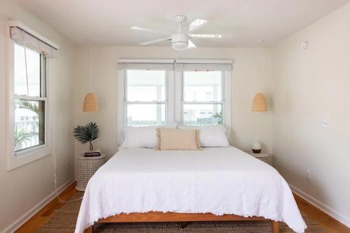a bedroom with a white bed with a ceiling fan at House of Kai in Carolina Beach