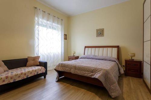 a bedroom with a bed and a couch and a window at Alloggi Villa Sarsina in Anzio