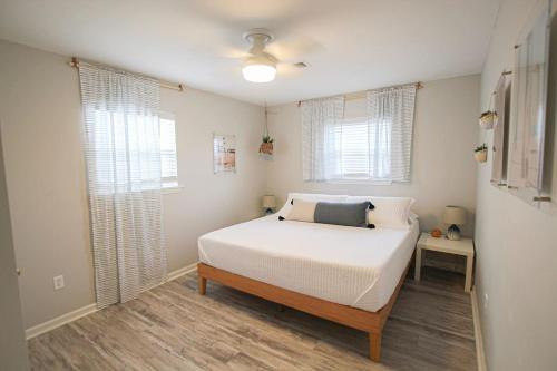 een slaapkamer met een wit bed en 2 ramen bij Sea-Esta in Kure Beach