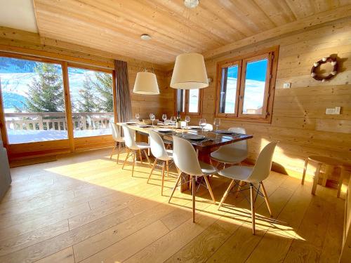 une salle à manger avec une table et des chaises blanches dans l'établissement Chalet Kiriolé, à Courchevel