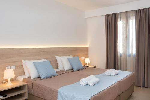 twee bedden in een hotelkamer met handdoeken erop bij Sunshine Village Hotel in Chersonissos