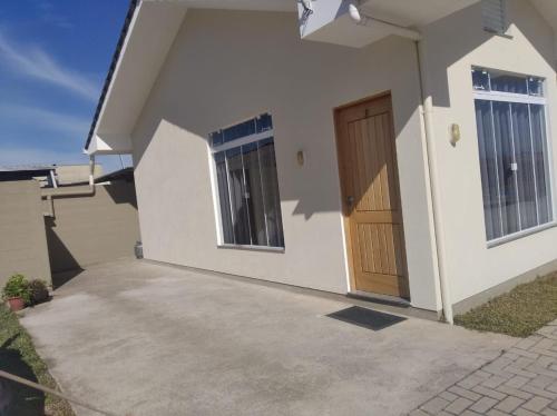 Casa blanca pequeña con puerta de madera en Cs9 Casa de 3 quartos a 15 min de Curitiba en Campina Grande do Sul