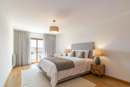 een witte slaapkamer met een bed en een raam bij Spacious and Chic Apartment with Lisbon, Sintra, or Beach at 15 min! in Amadora