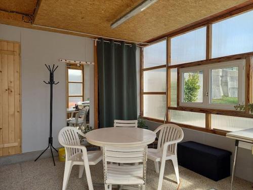 einen Tisch und Stühle in einem Zimmer mit Fenstern in der Unterkunft Gîte Lesmyosotis-messeix ***espace et calme 2/3p in Messeix