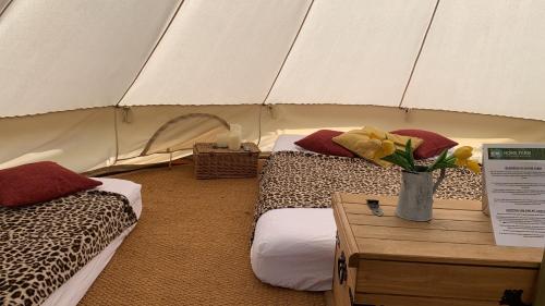 Zelt mit 2 Betten und einer Vase mit Blumen auf dem Tisch in der Unterkunft Home Farm Radnage Glamping Bell Tent 2, with Log Burner and Fire Pit in Radnage