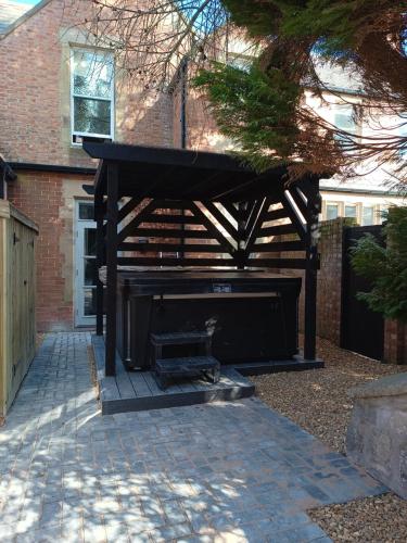 a wooden pavilion in front of a brick building at The West Wing at Eriviat Hall Hot Tub in Henllan