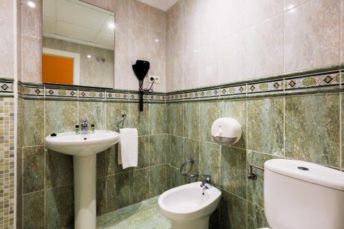une salle de bain avec un lavabo, des toilettes et un miroir dans l'établissement Hotel Tuto, à Torrevieja