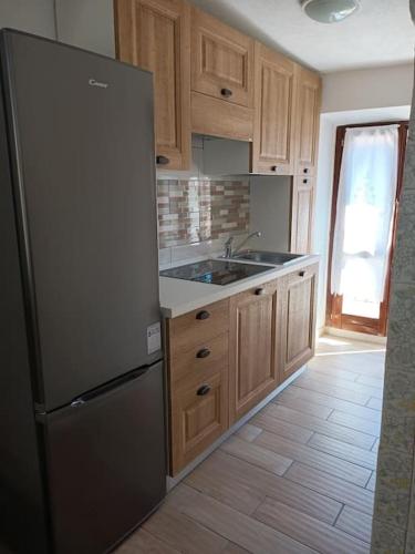 a kitchen with a stainless steel refrigerator and wooden cabinets at il telaio sardo Bonarcado in Bonarcado