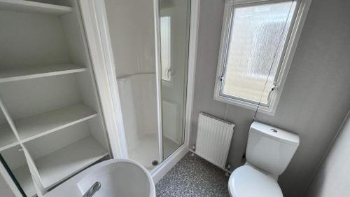 a small bathroom with a toilet and a window at 8 berth caravan PG214 Golden Palm Chapel st Leonards in Chapel Saint Leonards