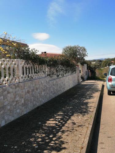 een stenen hek naast een weg met een auto bij My Nest in Arzachena