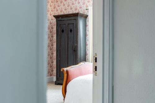 a bedroom with a bed and a wooden cabinet at The Whichcote Arms in Osbournby