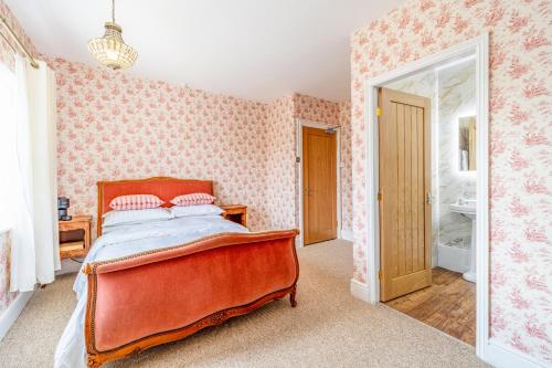um quarto com uma cama e papel de parede rosa em The Whichcote Arms 