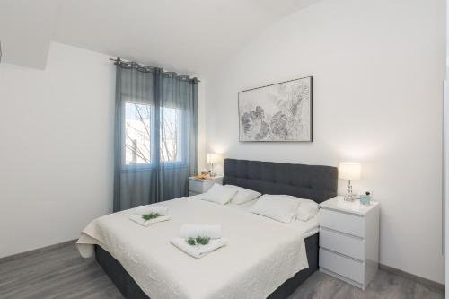 biała sypialnia z dużym łóżkiem z białą pościelą w obiekcie Apartments Marina w Bibinje
