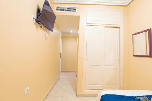 Habitación con puerta y TV en la pared en Hotel Tuto, en Torrevieja