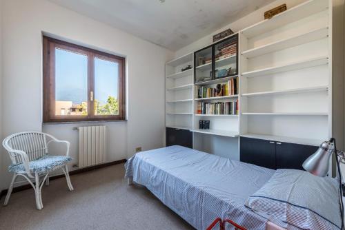 ein Schlafzimmer mit einem Bett, einem Stuhl und Bücherregalen in der Unterkunft Casa Angela in San Felice del Benaco