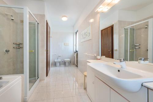 ein weißes Bad mit einem Waschbecken und einer Dusche in der Unterkunft Casa Angela in San Felice del Benaco