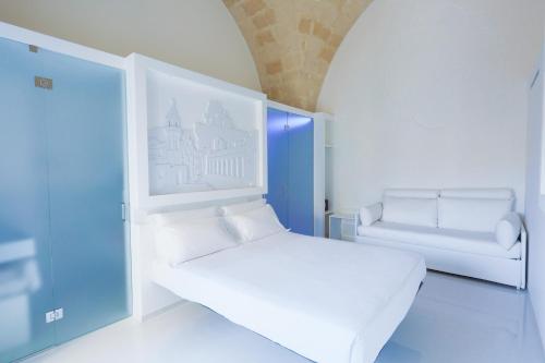 a white room with a bed and a chair at Vittorio Veneto Matera Luxury Rooms in Matera