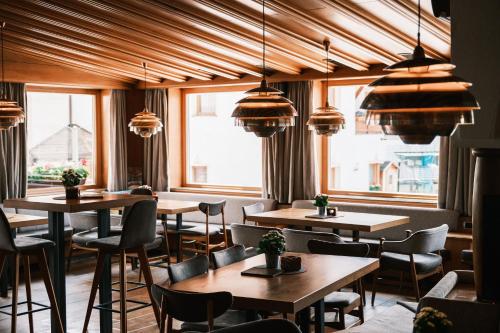 a restaurant with tables and chairs and windows at Kristiania Small Dolomites Hotel in Selva di Val Gardena