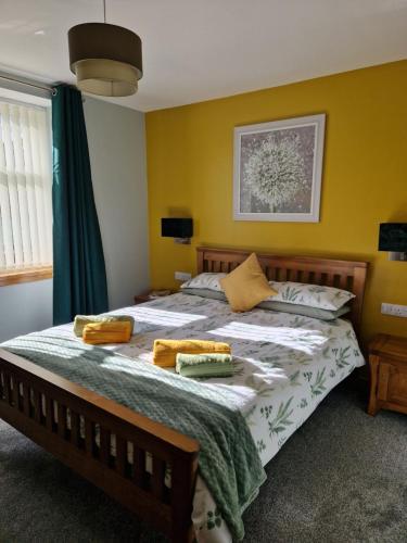 um quarto com uma cama grande e paredes amarelas em deesideholidaycottages em Dinnet