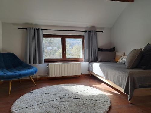 a bedroom with a bed and a chair and a window at La cabane d'Achille - La Roche-en-Ardenne in La Roche-en-Ardenne
