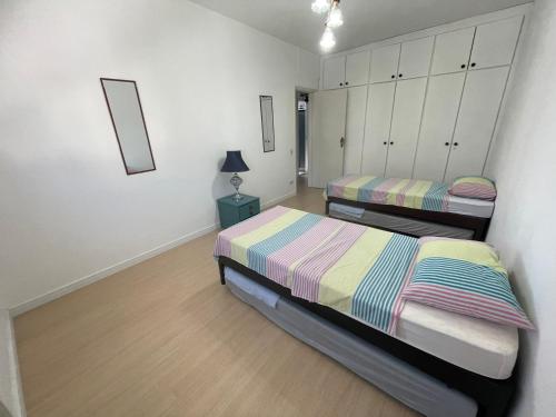a bedroom with two beds and a lamp in it at Praia Gonzaga, Santos in Santos