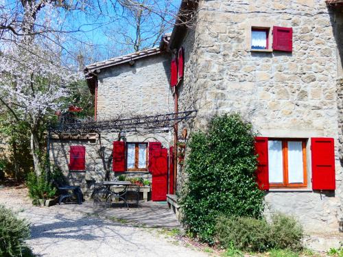 a stone house with red shuttered windows and a table at La Baronessa Country House in Montefiascone
