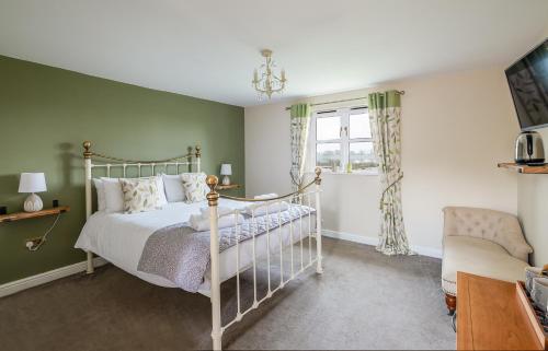 a bedroom with a bed and a tv and a chair at White Hart Inn in Blythburgh