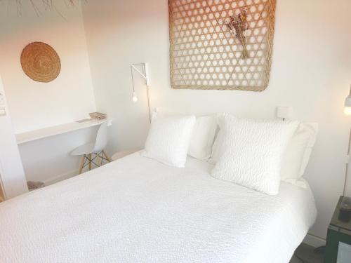 a bedroom with a white bed with white pillows at Blanc Sable Hôtel in Golfe-Juan