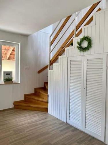 a living room with a staircase with white walls and wood floors at Zen Garden Szajki Tavak in Hosszúpereszteg