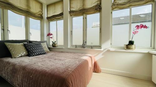 a bedroom with windows and a bed with a pink blanket at ApartmentInCopenhagen Apartment 1533 in Hellerup