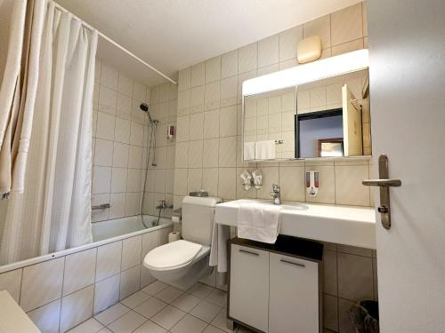 a bathroom with a toilet and a sink and a tub at Seehotel Riviera at Lake Lucerne in Gersau