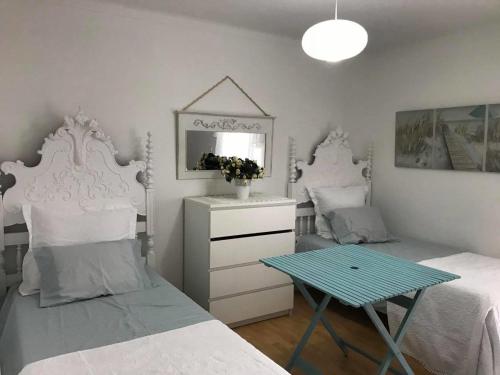 a bedroom with two beds and a table and a mirror at Margarita´s Ville in Costa Nova
