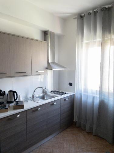 a kitchen with a sink and a window with curtains at Lamezia Park Apartments in Lamezia Terme