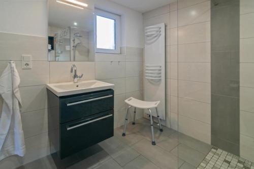 a bathroom with a sink and a shower and a stool at Ferienwohnung-Moewenblick in Norden